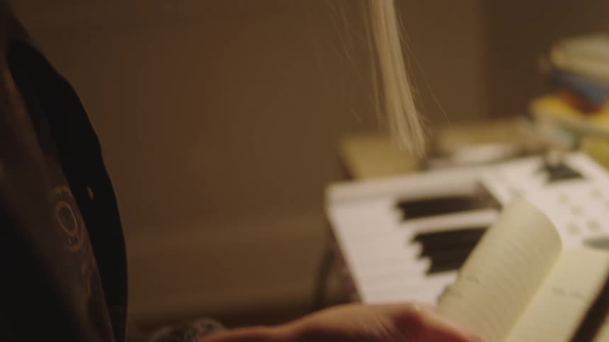 A lady writing on a book while seated indoor