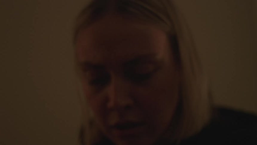 Woman breaking a cassette tape on a dimly lit room