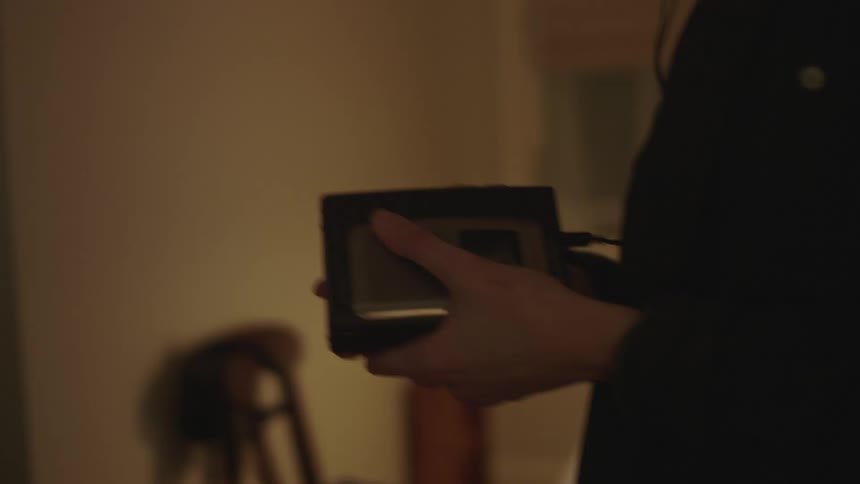 Woman walks back and forth in room listening to cassette player on headphones