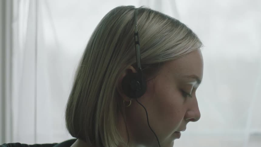 Closeup of a blonde womans face putting on headphones