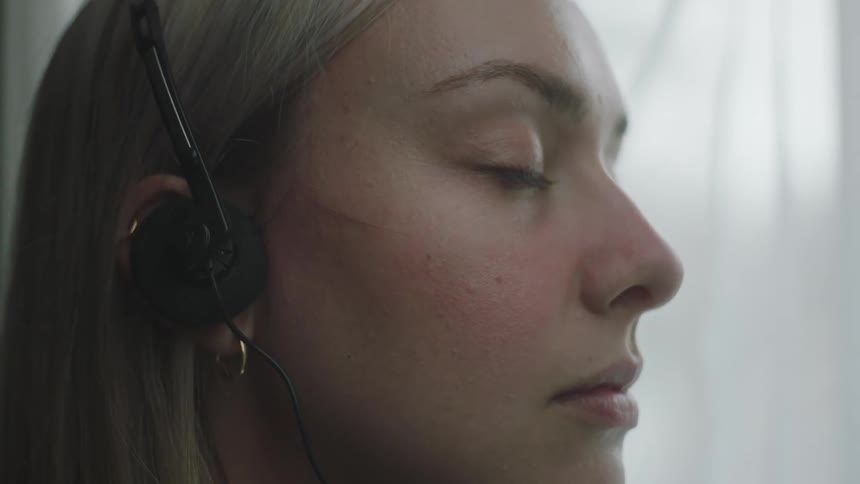A closeup of a blonde womans face wearing headphones
