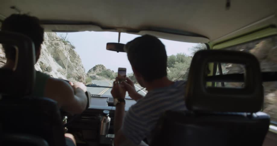 Friends driving on a road between the hills