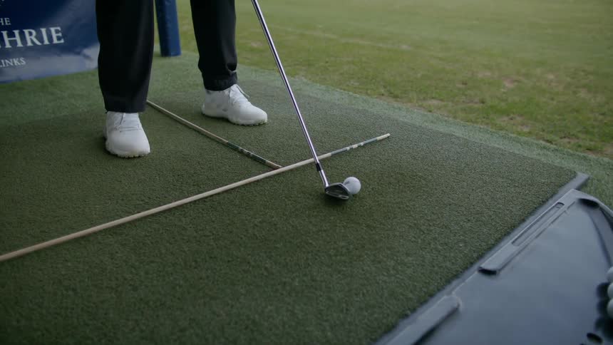 Person swinging a golf club hitting a white golf ball