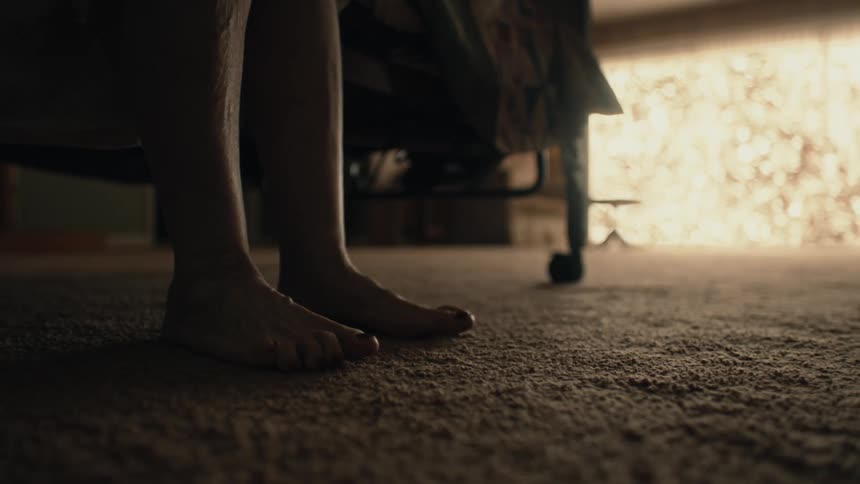Closeup of a womans feet touching the rug on the floor getting out of bed