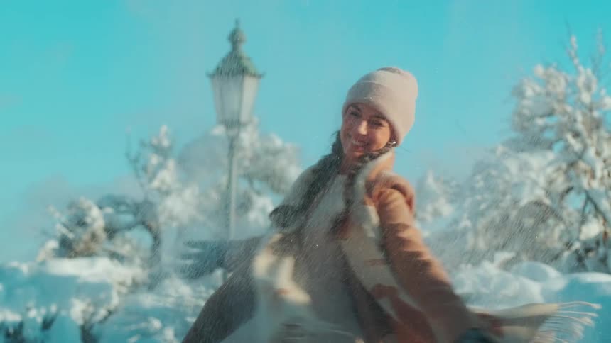 A smiling woman playing with the snow