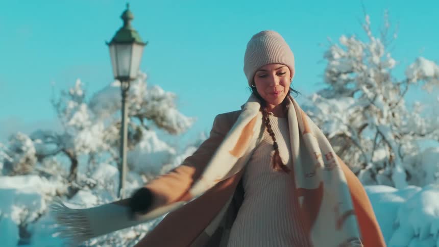 A woman spinning her body in a snowy environment on a clear cloudless day