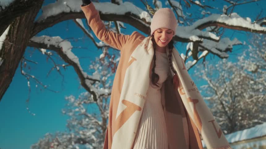 A smiling woman playing in the snow on a sunny day