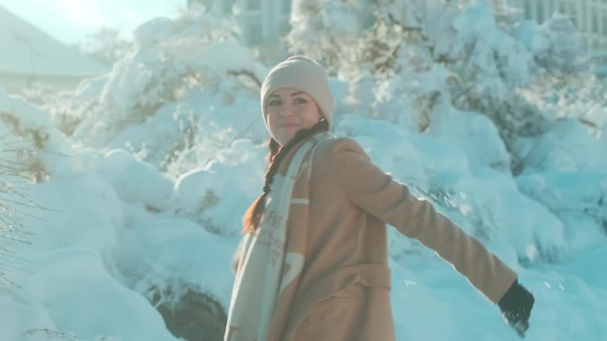 Woman scooping up snow with her hands forming a snowball and throwing it