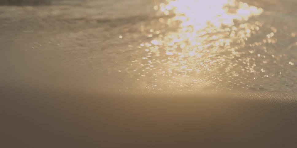 The setting sun is reflecting on sand and water