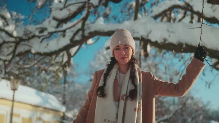 A woman pulls on the branch and snow falls all over her