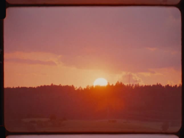 The sun is rising behind the forest
