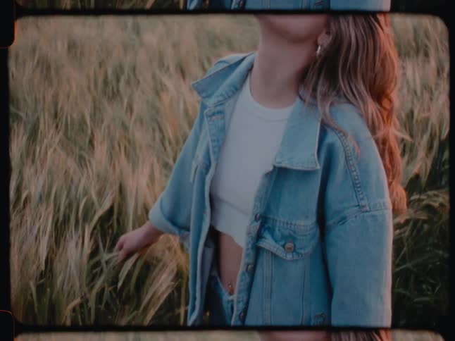 Woman models denim outfit in field outdoors