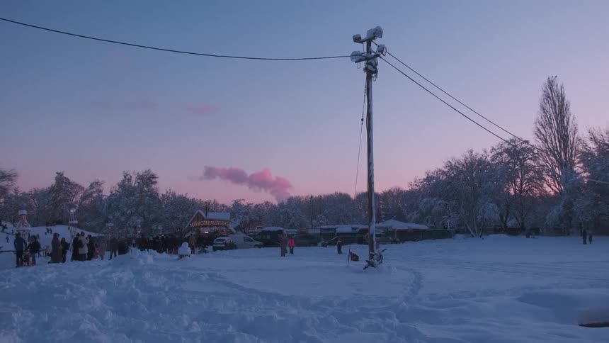A crowd in front of a house with flashing lights covered in snow