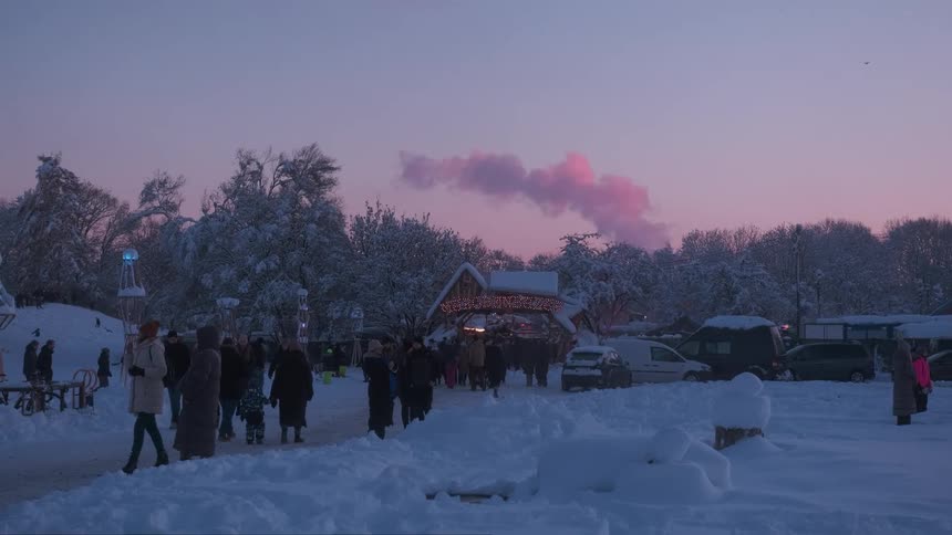 People walking in a snowcovered park on a day with a purple sky