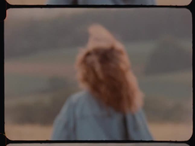 Woman running through a wheat field viewed from behind