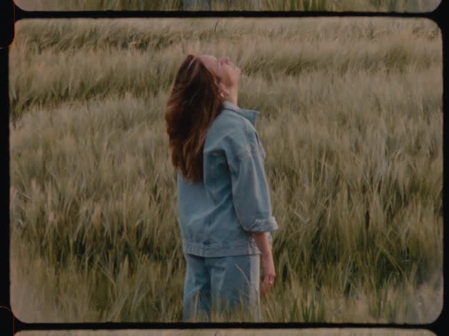A woman is stand on the field of tall grass