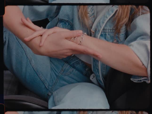 A woman wearing a denim jacket and jeans rubs her hands