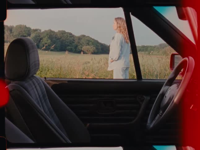 View from inside a car of a woman next to a field