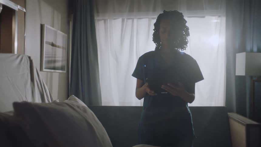 A doctor typing on a tablet in a hospital room