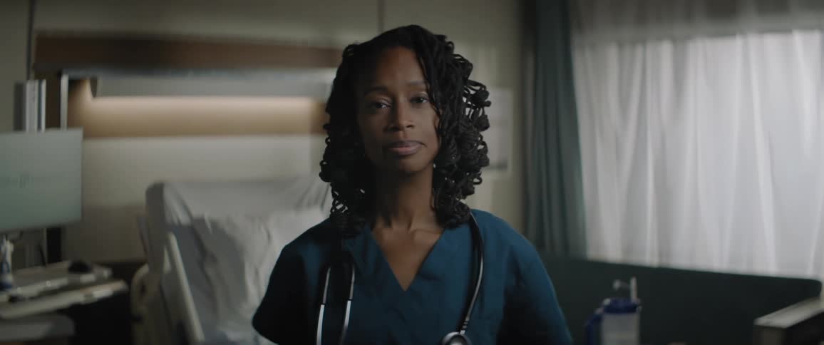 A black female doctor smiling as a white nurse walks behind her