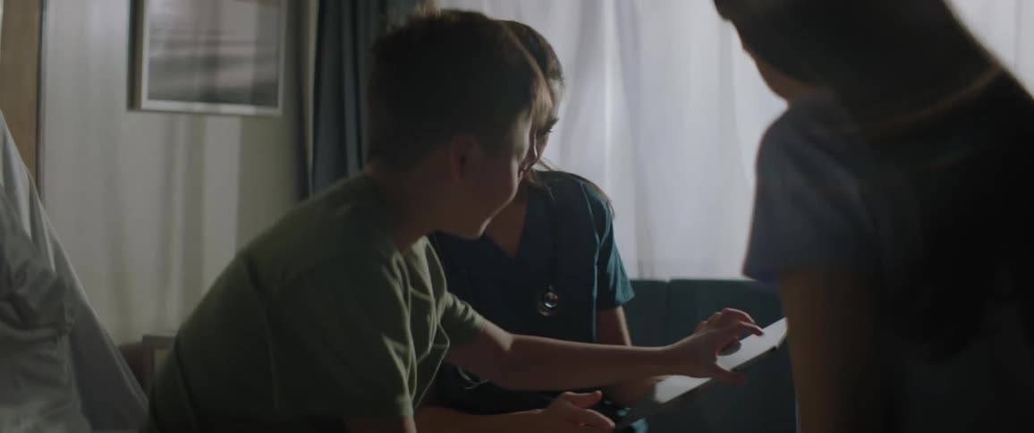Nurse holding a tablet with a boy beside her while the boys mother uses the tablet