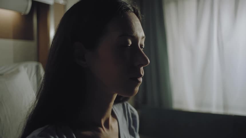 Female patient sitting on the bed with her eyes closed