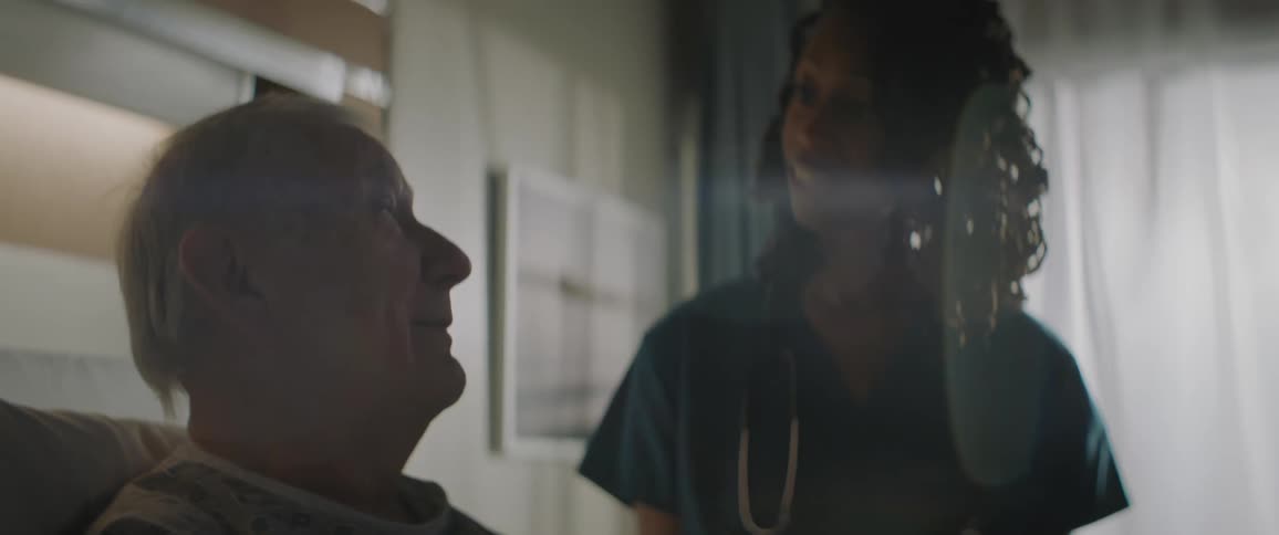 Nurse talking to the elderly patient sitting on the bed