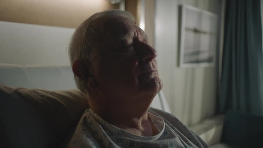 An elderly patient takes a deep breath while lying in bed