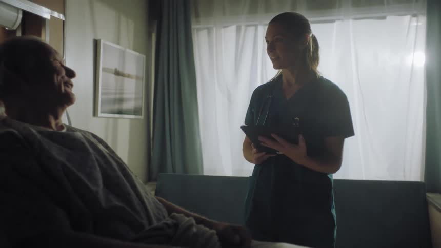 A nurse stands by the patient asking questions in the hospital room