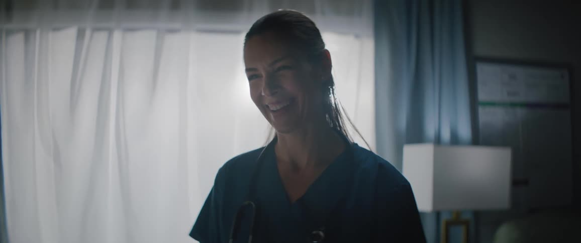 A nurse with a ponytail and a stethoscope listens to the patient and laughs