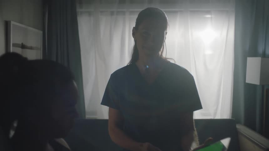 Nurse showing something on a tablet to a patient sitting in bed