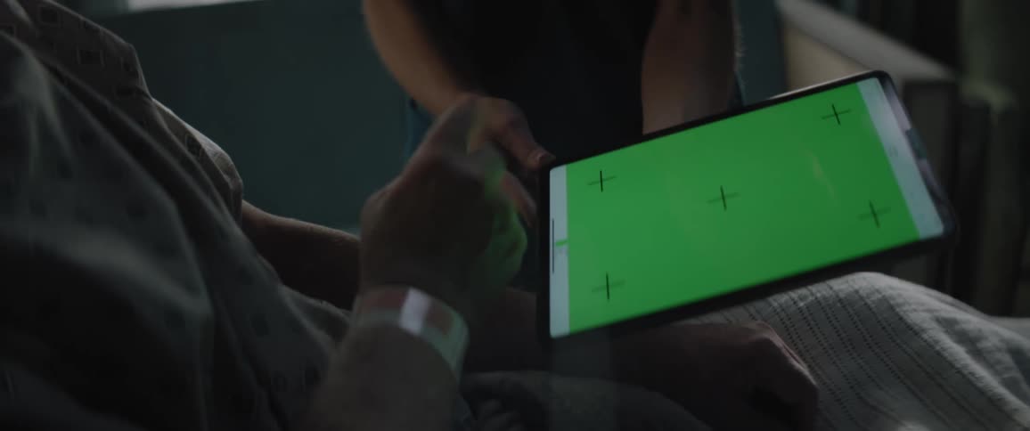 A medical professional holds a tablet computer for a patient to review