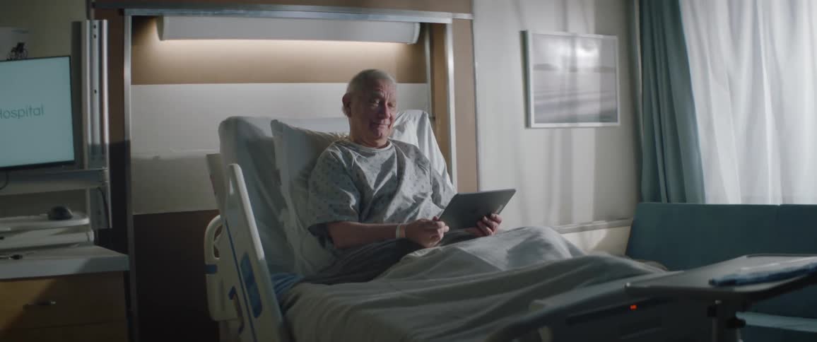 A patient in the hospital is laughing at the tablet