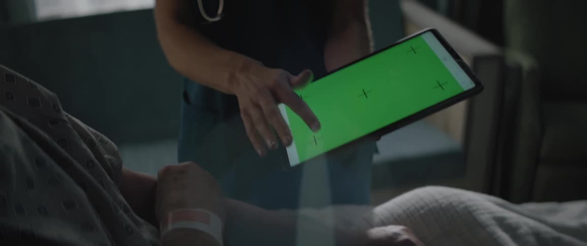 A female medical professional holds a tablet for a patient to see