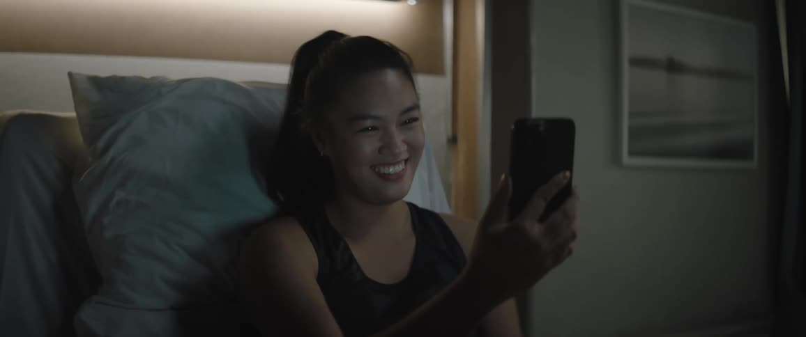 A woman sitting on the bed makes a video call on her smartphone
