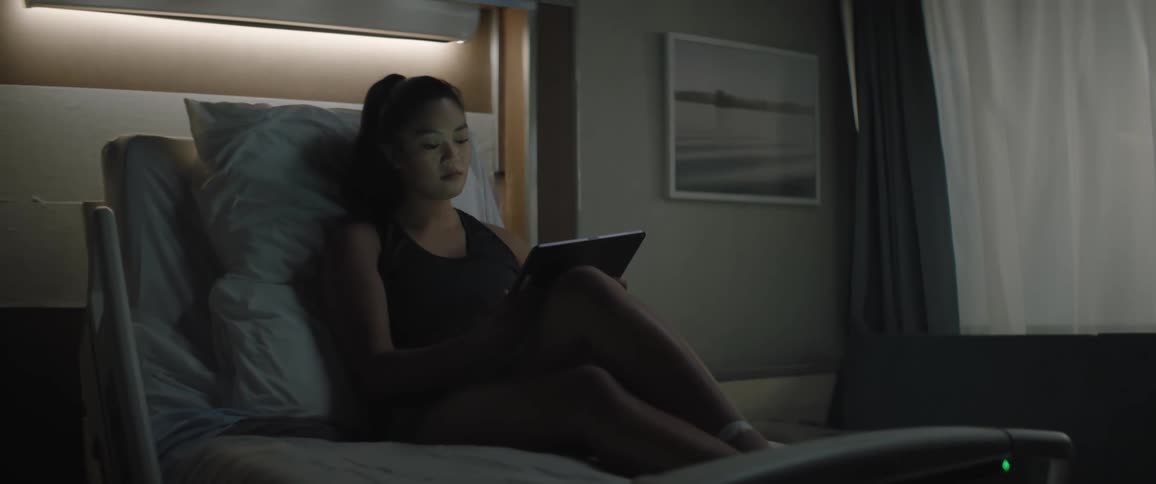 A female sitting on an hospital bed operating an ipad