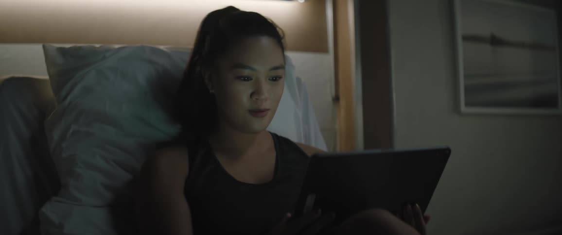 Woman with a ponytail sits on hospital bed using a tablet