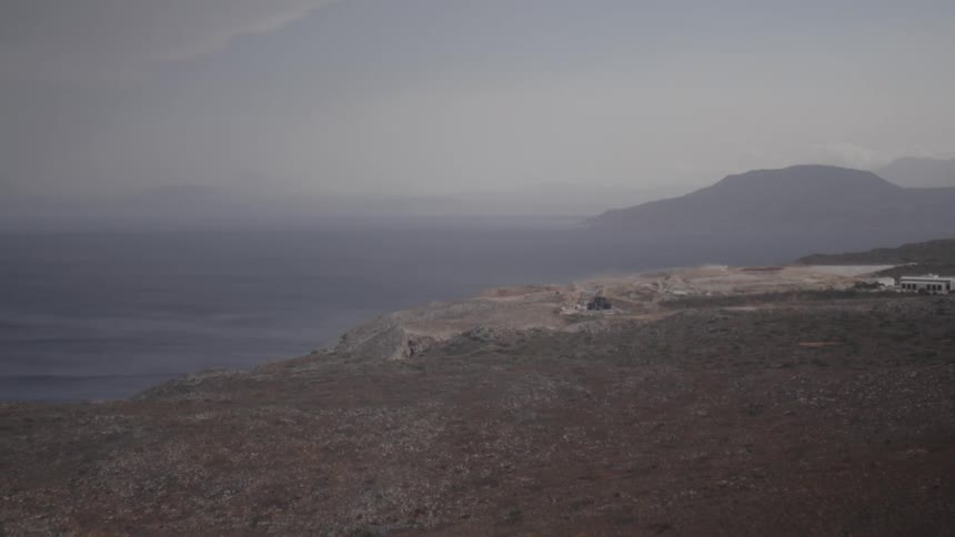 A vehicle on the edge of a mountain facing the sea