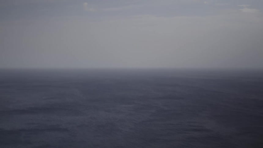 Waves roll in under a hazy sky