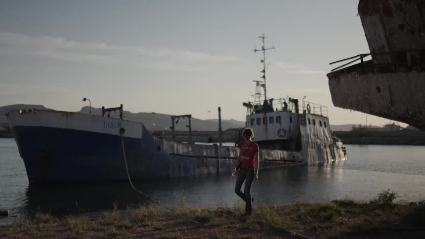Woman walking on the ground next to a stranded ship in the sea