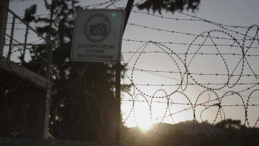 View of a sign prohibiting cameras amidst barbed wire in the morning