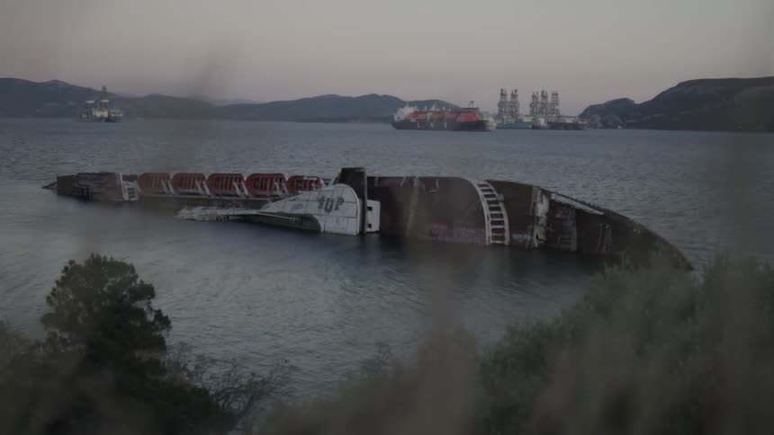 Shipwreck in water with hills on horizon