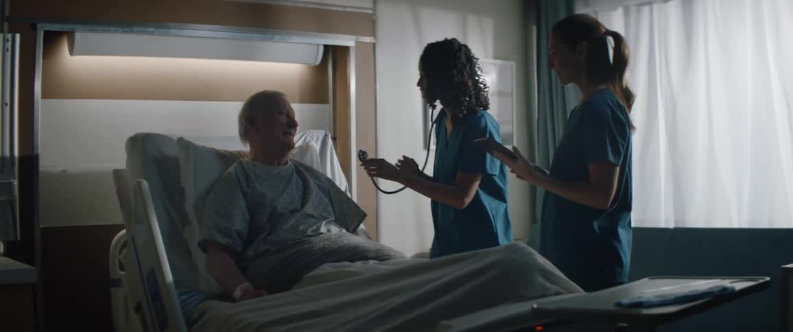 A doctor and nurse examine a patient in a hospital room
