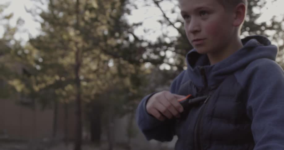 A boy holds a walkie talkie to his chest outside