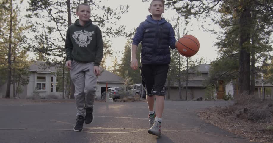 Young boys dribble a basketball down a neighborhood street