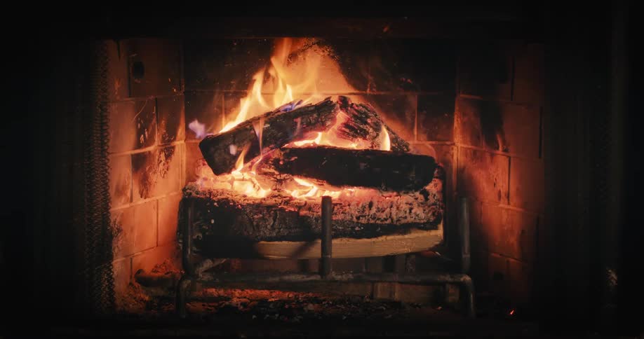 Logs burning in a fireplace at night creating a warm glow