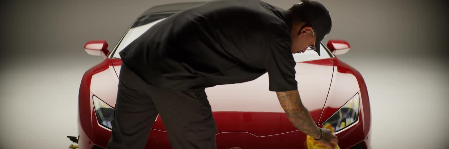 A man is cleaning a car with a rag