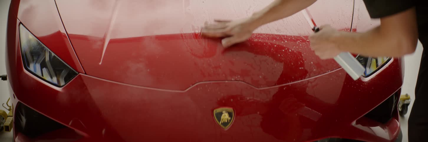 A man is cleaning a car with a spray bottle