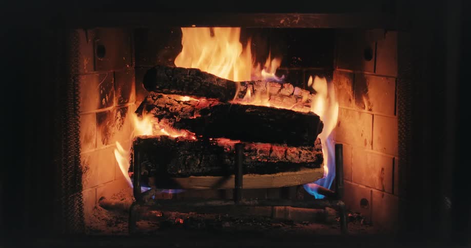 A fireplace with fire burning several logs