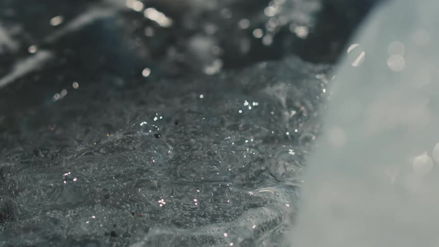 A piece of ice in water with a small ripple hitting it